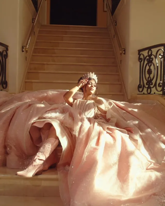 Quinceañera in a blush gown resting on the estate’s grand staircase