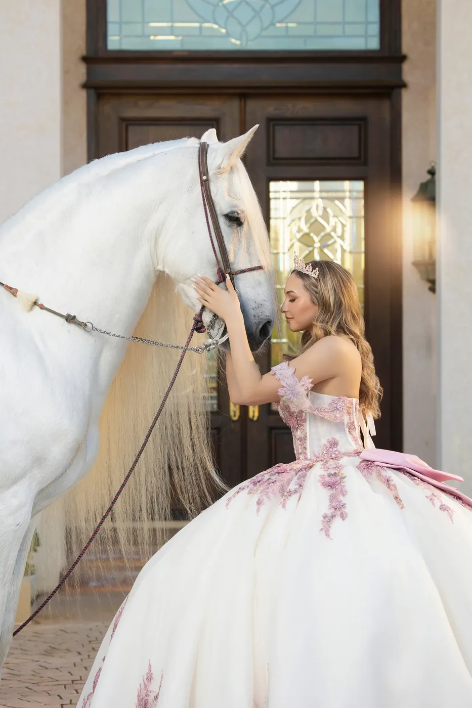 Quinceañera in a pink and white gown with a white horse
