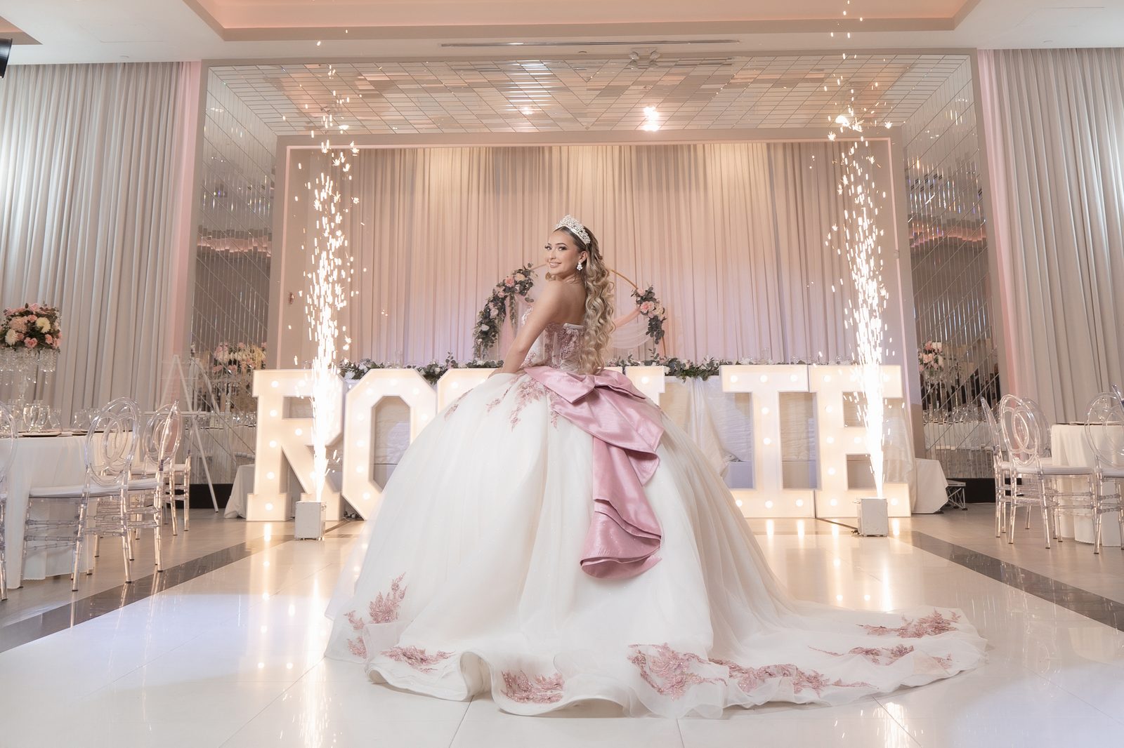 An ivory ball gown in a ballroom, her name spelled in marquee letters