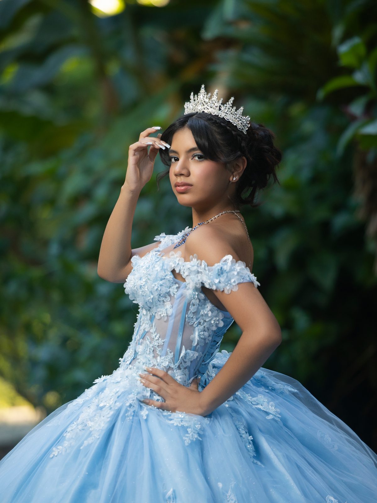 A sky-blue gown and a jeweled tiara in a garden